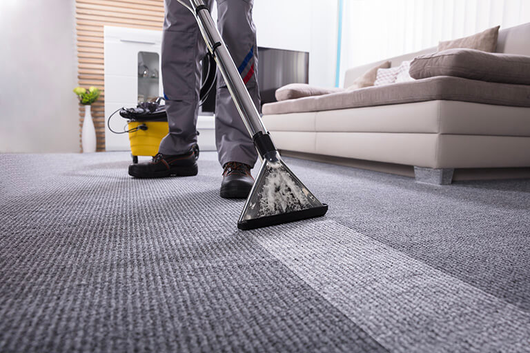 Technician using a hot water extraction wand to steam clean carpet in a Lehi home
